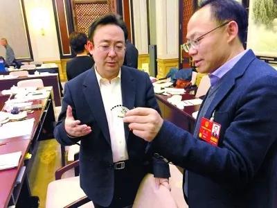 昨天,北京團(tuán)小組會休息的間隙,程京代表(右)向夏林茂代表介紹基因芯片。張宇攝
